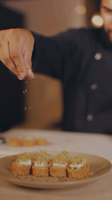 Chef finalizando peças de sushi num prato